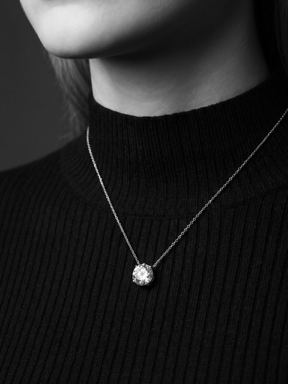Round diamond solitaire pendant on a fine chain at the collarbone