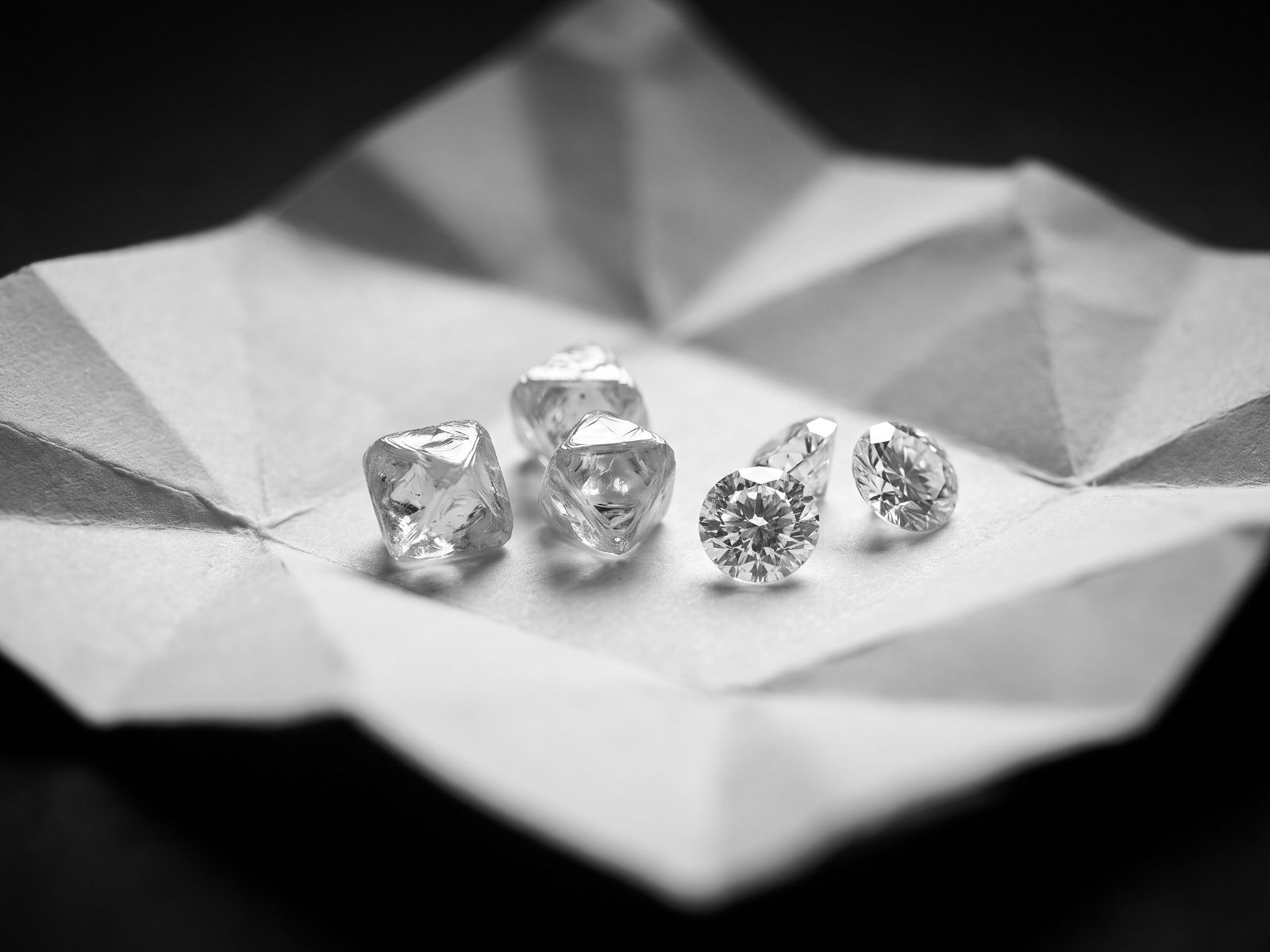 Rough and polished diamonds side by side on paper parcels