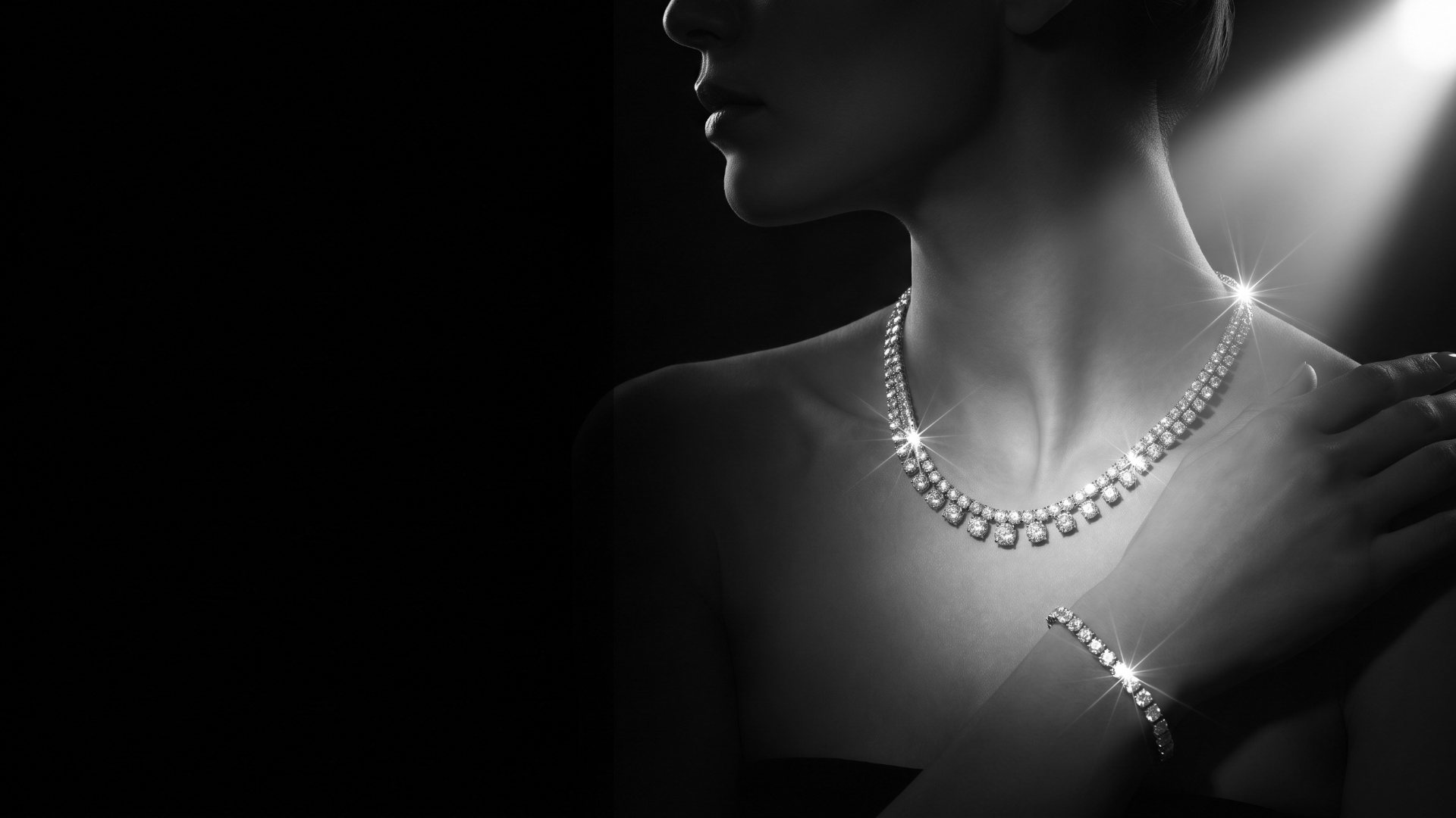 Woman in a spotlight wearing a graduated diamond riviera necklace and a diamond tennis bracelet