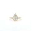 The 1.59ct Pear Lab Grown Diamond Bezel Engagement Ring, featuring a gold band, is showcased against a plain white background with the diamond elegantly set in a sleek, modern bezel setting.