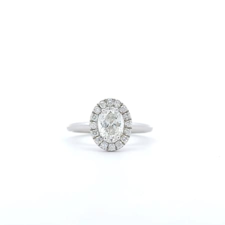 The 1ct Oval Natural Diamond Halo Engagement Ring is showcased on a white background, featuring a stunning silver design with an oval-shaped diamond center stone encircled by a halo of smaller diamonds on a simple band.