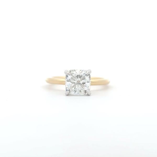 A gold engagement ring with a 2-carat cushion-cut natural diamond and hidden halo is set in a four-prong setting against a plain white background.