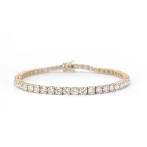 This 5.27ct lab-grown diamond tennis bracelet, set in 14k yellow gold, features a continuous line of dazzling round diamonds against a white background. Elegantly crafted, it showcases a classic and sophisticated design.