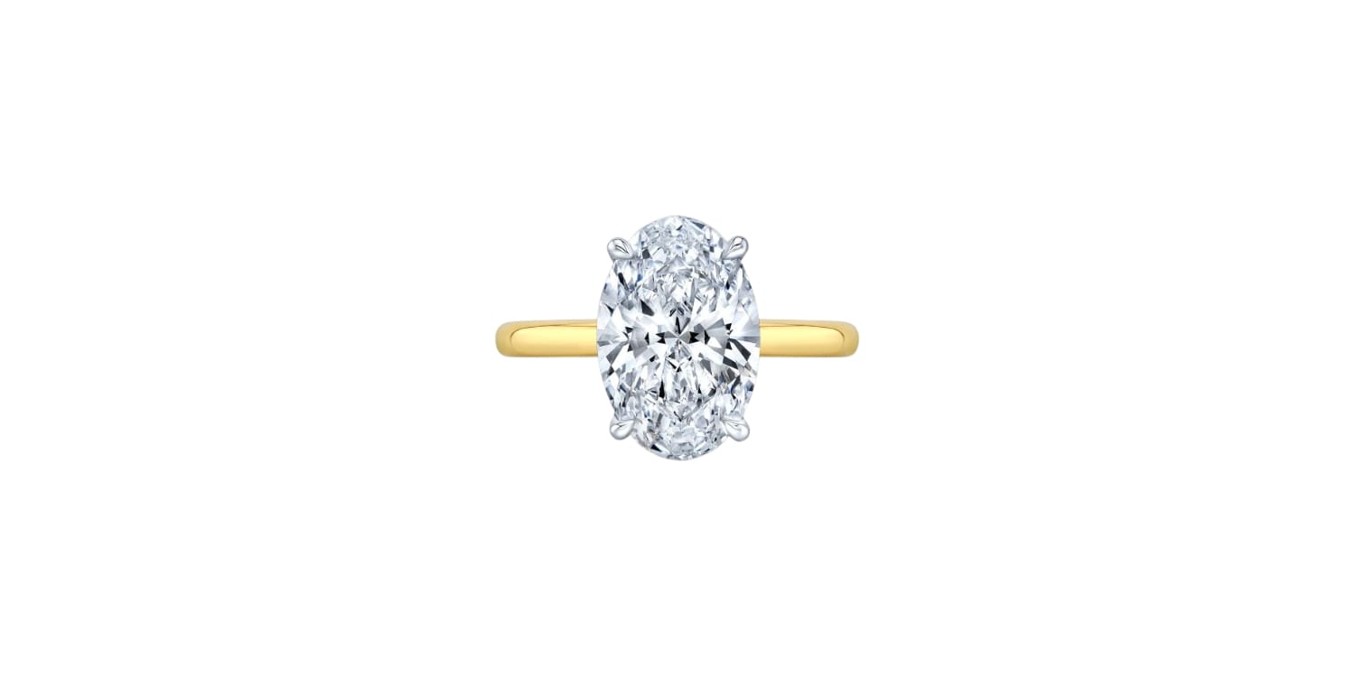 A gold ring with an oval-cut diamond centerpiece displayed on a white background.