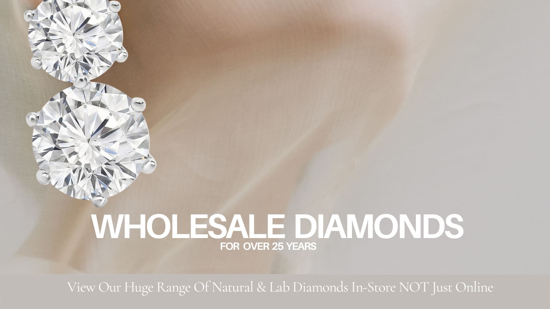 Close-up of two sparkling diamonds with text reading "Wholesale Diamonds for Over 25 Years." Below, there's a note: "View Our Huge Range Of Natural & Lab Diamonds In-Store NOT Just Online." The background is soft and blurred.